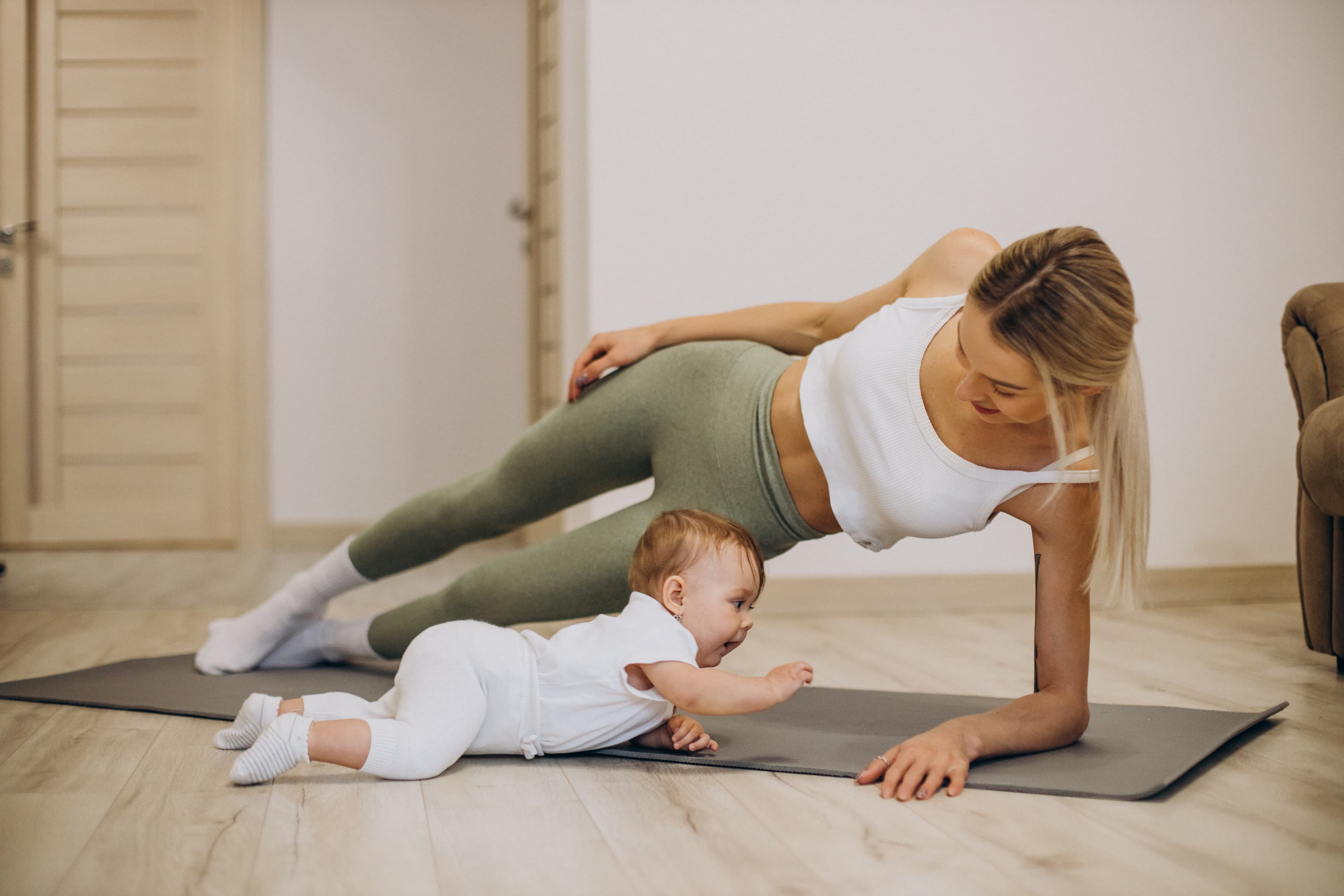 Mother and baby doing postnatal yoga together at home